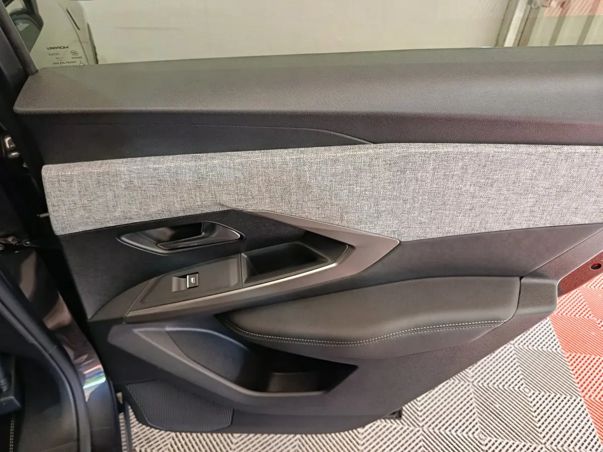 Panneau de porte côté gauche en tissu gris et cuir noir du Peugeot 3008 1.2 HYBRID 145 E-DCS6 GT noir, vue intérieure.