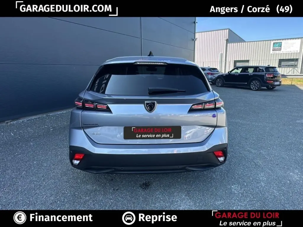 Vue arrière d'une Peugeot 308 gris clair 2023 avec feux LED et logo lion distinctif.