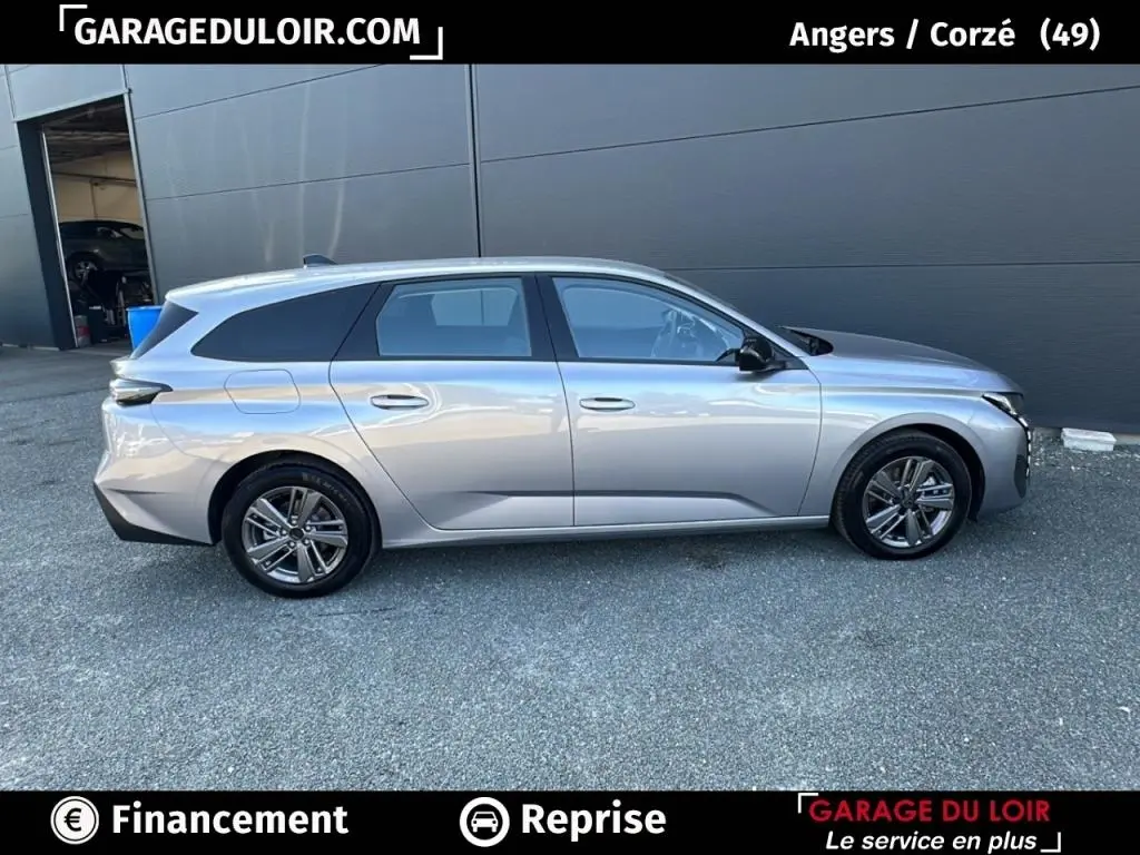 Peugeot 308 gris clair vue de profil côté gauche, break avec jantes alliage et vitres teintées.