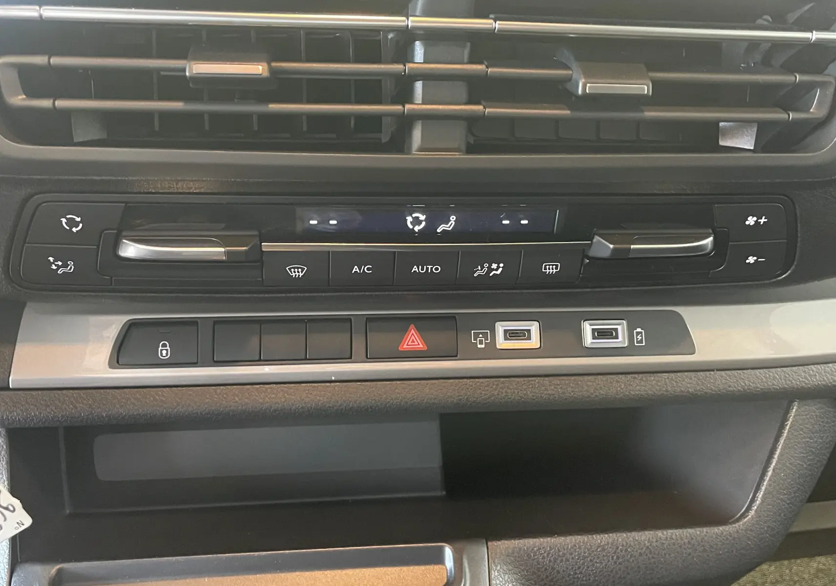 Vue rapprochée du tableau de bord du Peugeot Traveller 2026, mettant en valeur les commandes de climatisation et les ports USB.