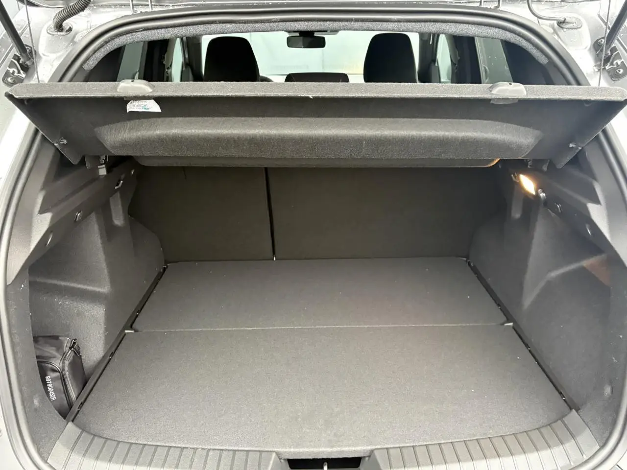 Coffre ouvert du Dacia Duster gris schiste 2026, vue arrière montrant l'espace de chargement avec cache-bagages déployé.