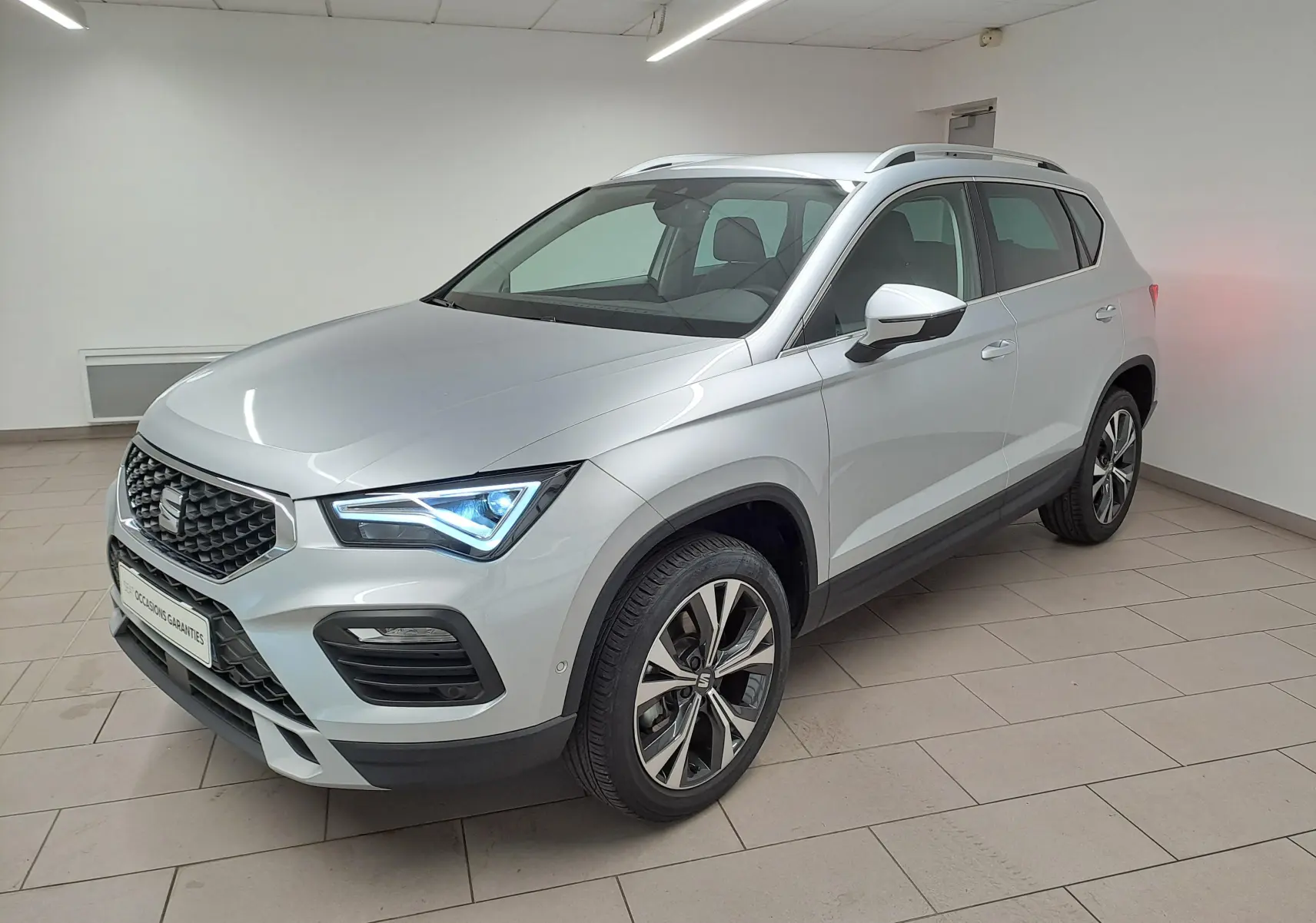 SEAT Ateca 2.0 TDI 150 DSG7 Copa en Argent Reflex, vue 3/4 avant avec jantes alliage 18'' usinées et phares allumés.