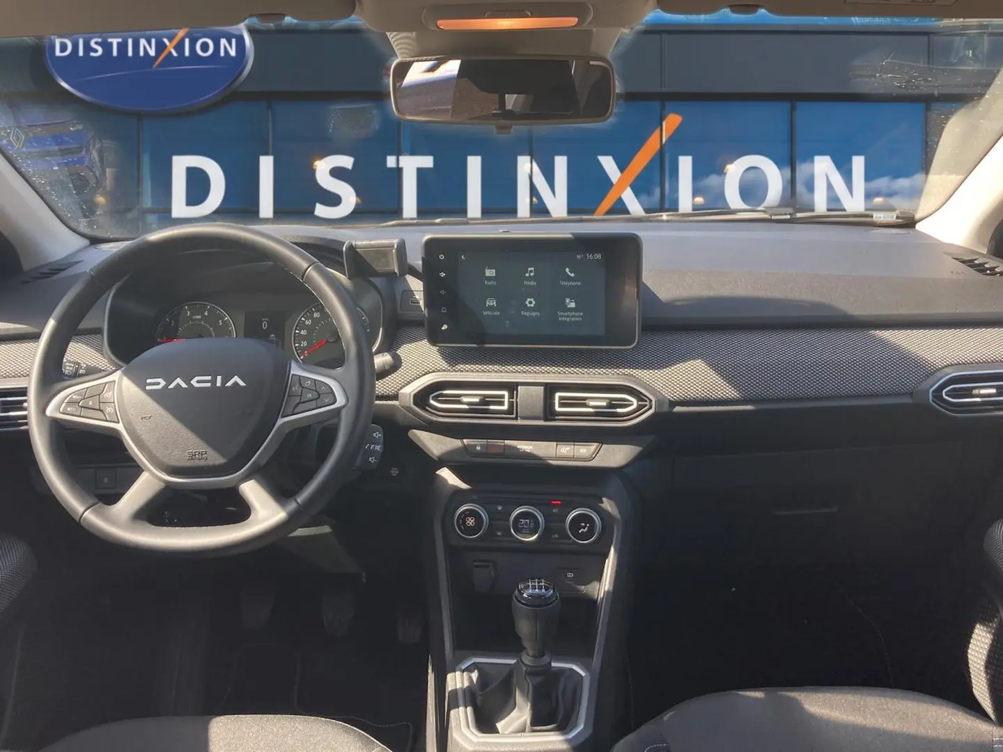 Vue intérieure avant de la Dacia Sandero 2025, tableau de bord noir avec écran tactile et volant multifonctions.