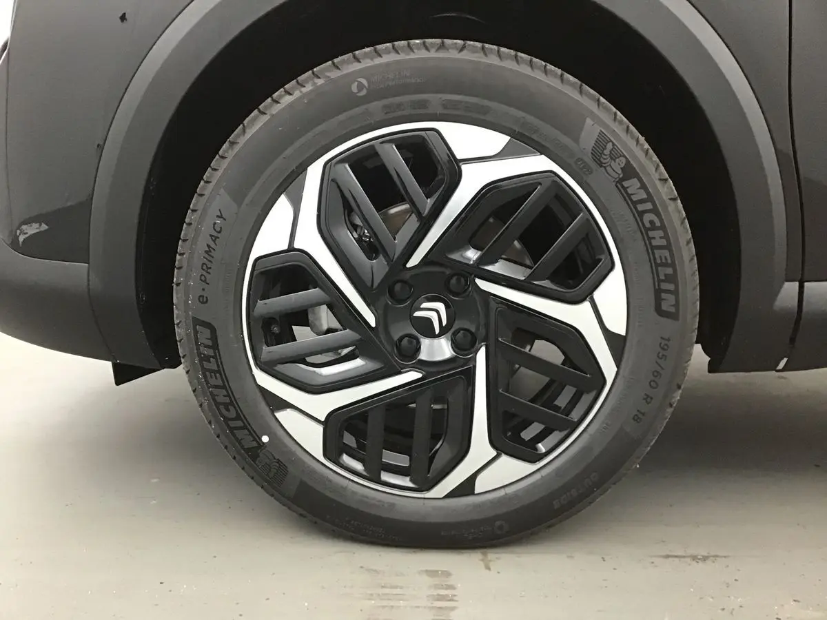 Gros plan sur la jante avant gauche noire et argentée du Citroën C4 noir de 2022 avec pneu Michelin.