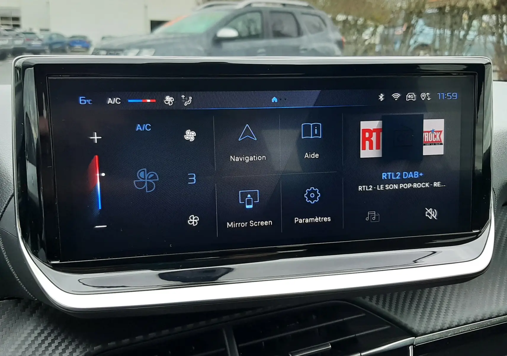 Écran tactile central de la Peugeot 208 2024 affichant la climatisation, navigation et radio, avec tableau de bord en carbone.