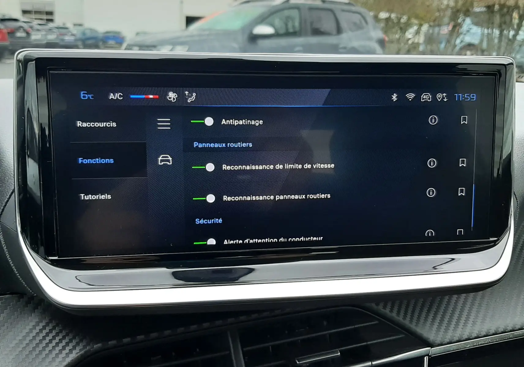 Écran tactile central de la Peugeot 208 2024 affichant les options d'assistance à la conduite, avec tableau de bord noir et finition carbone.