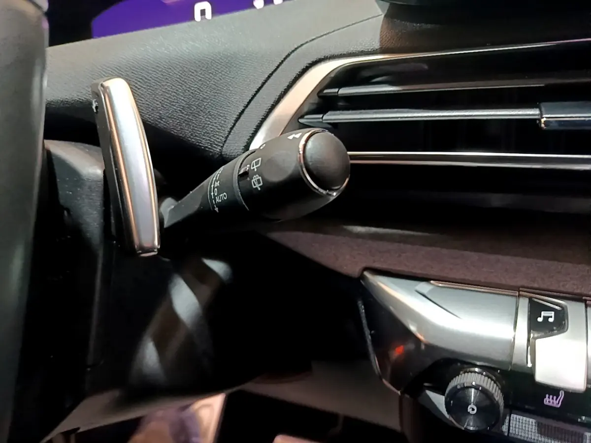 Gros plan sur la commande d’essuie-glace à gauche du volant dans l’habitacle noir du Peugeot 3008 GT 2023.