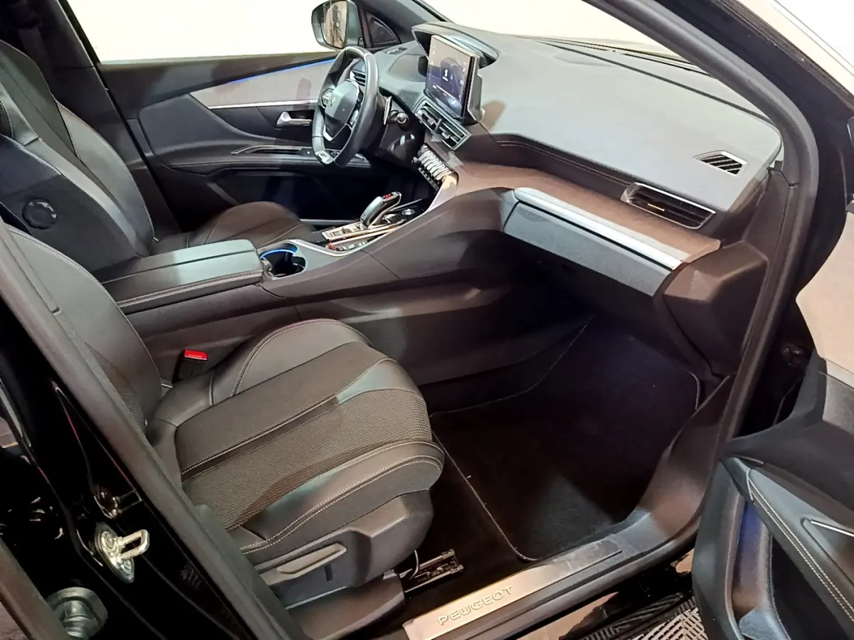 Intérieur côté passager du Peugeot 3008 noir 2023, avec tableau de bord moderne et sièges en tissu noir.