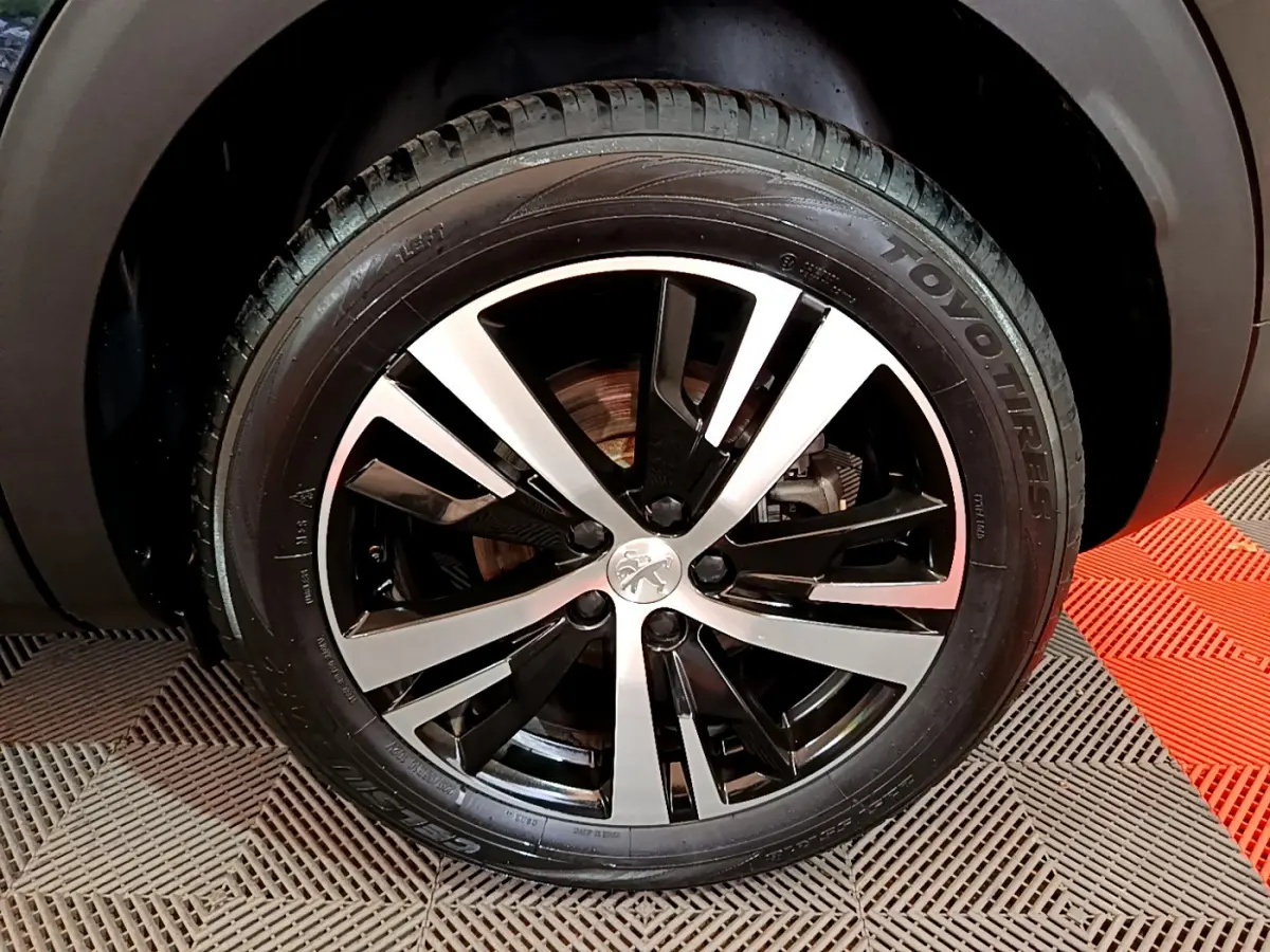 Gros plan sur la jante alliage bicolore noire et argentée d'un Peugeot 3008 noir, pneu Toyo visible.