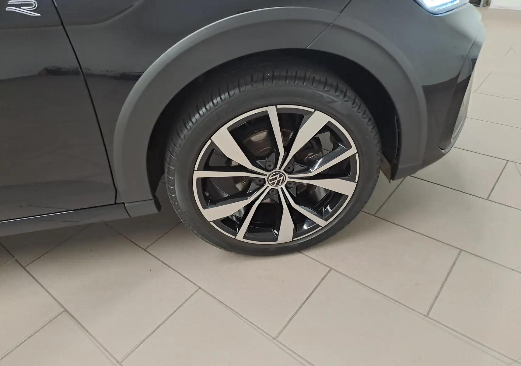Gros plan sur la roue avant gauche du Volkswagen Taigo noir intense 2025 avec jante alliage léger 18'' Misano et logo R-Line visible.