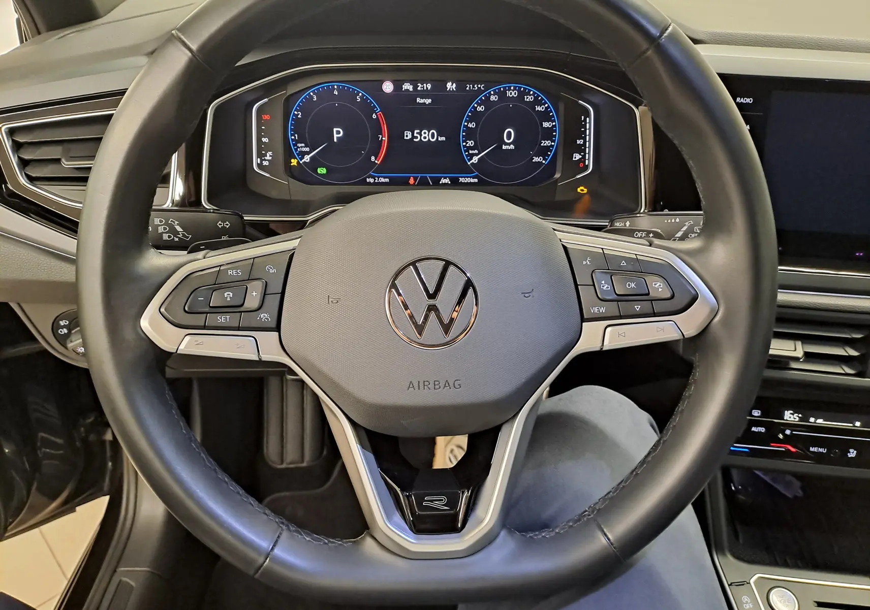 Vue intérieure centrée sur le volant cuir noir du Volkswagen Taigo 2025 avec tableau de bord numérique et commandes intégrées.