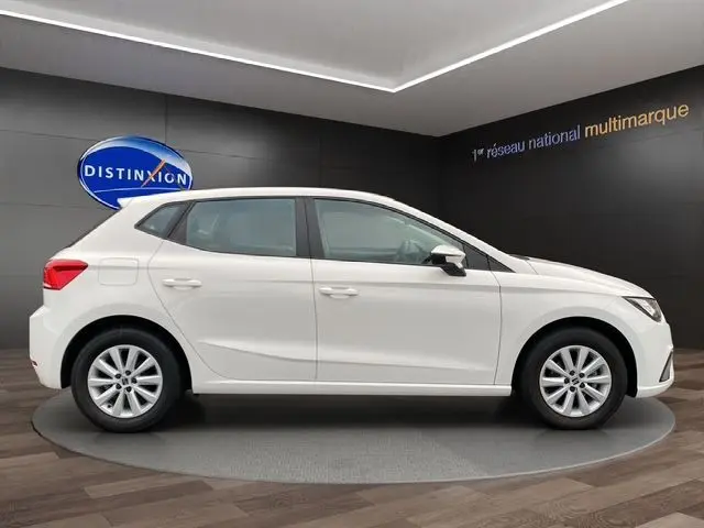 Profil latéral droit d'une SEAT IBIZA 2023 blanc candy, compacte cinq portes exposée en showroom moderne.