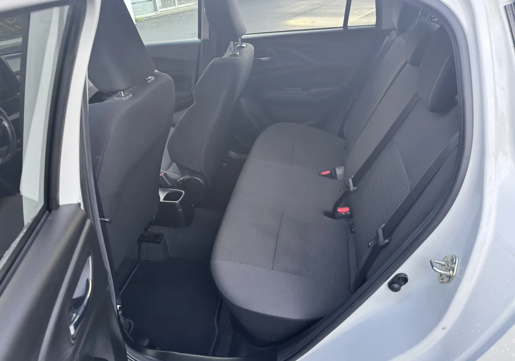 Vue intérieure côté droit montrant la banquette arrière noire d'une Suzuki Swift 1.2 Privilège blanche 2025 avec porte ouverte.