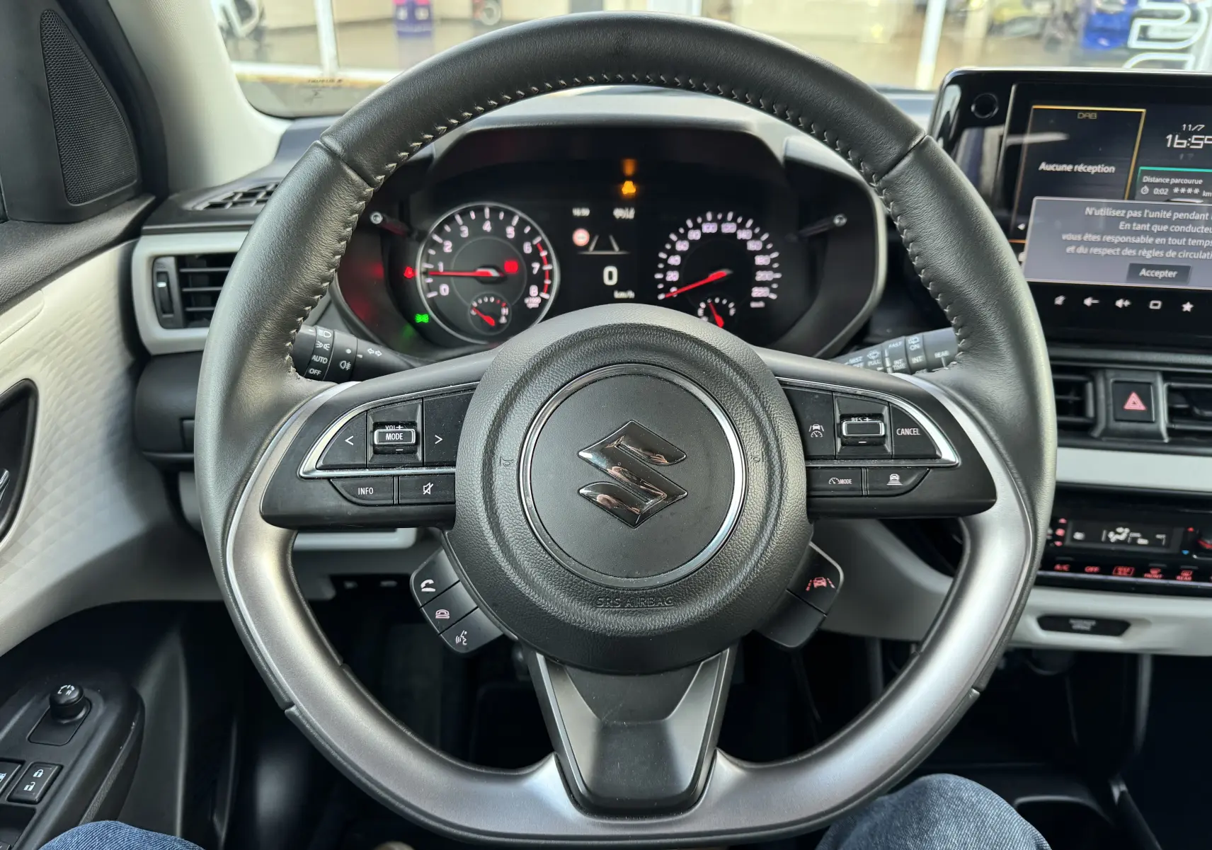 Vue centrée sur le volant noir du Suzuki Swift 1.2 Privilège 2025 avec tableau de bord et écran tactile visibles.