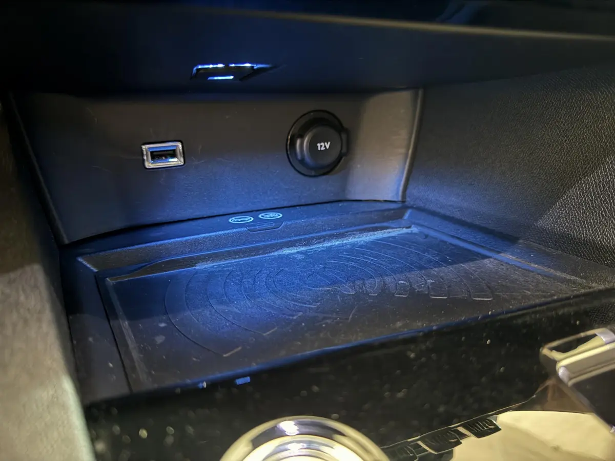 Vue rapprochée de la console centrale du Peugeot 3008 gris clair, avec prise USB, prise 12V et zone de recharge sans fil.