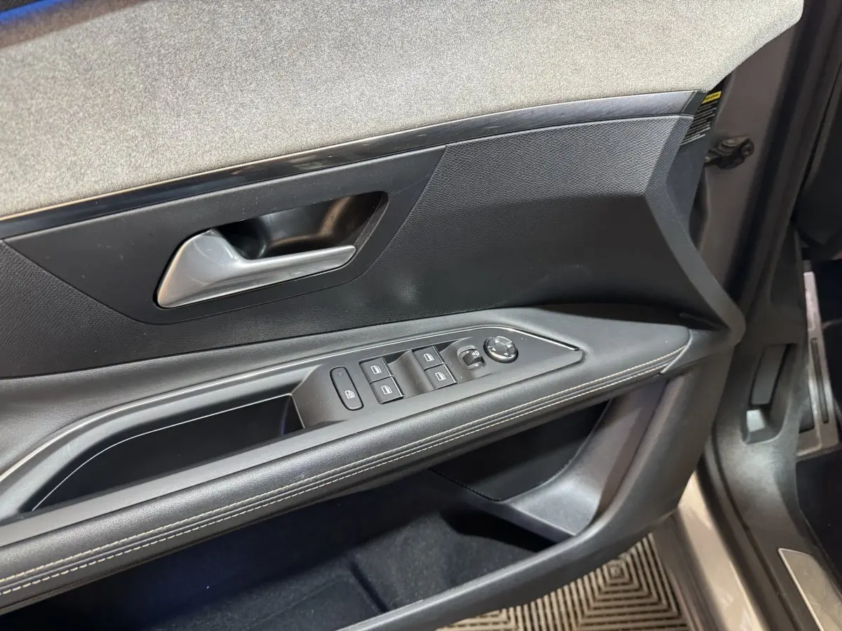 Vue rapprochée de la porte côté gauche du Peugeot 3008 gris clair, montrant les commandes des vitres et rétroviseurs.