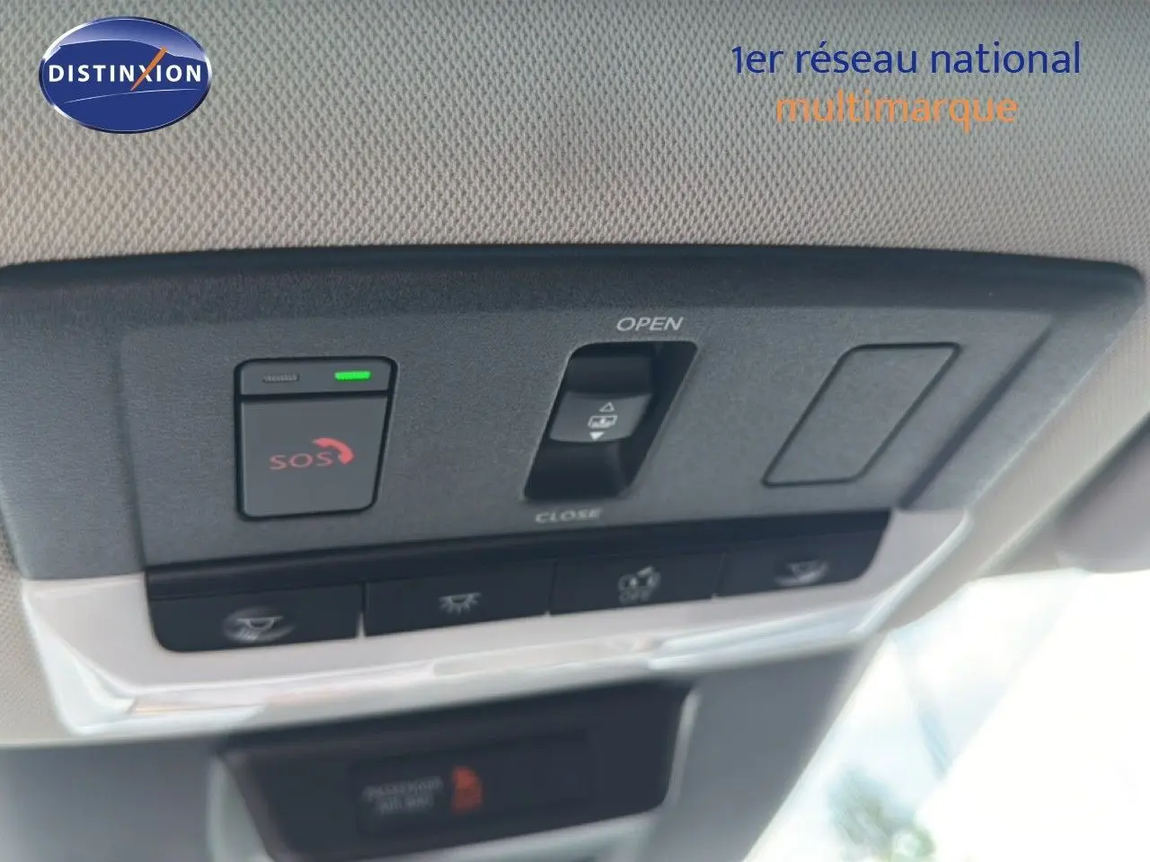 Vue en gros plan du panneau de commandes au plafond intérieur du Nissan Qashqai blanc nacré 2023, avec bouton SOS et commande d'ouverture de toit ouvrant.