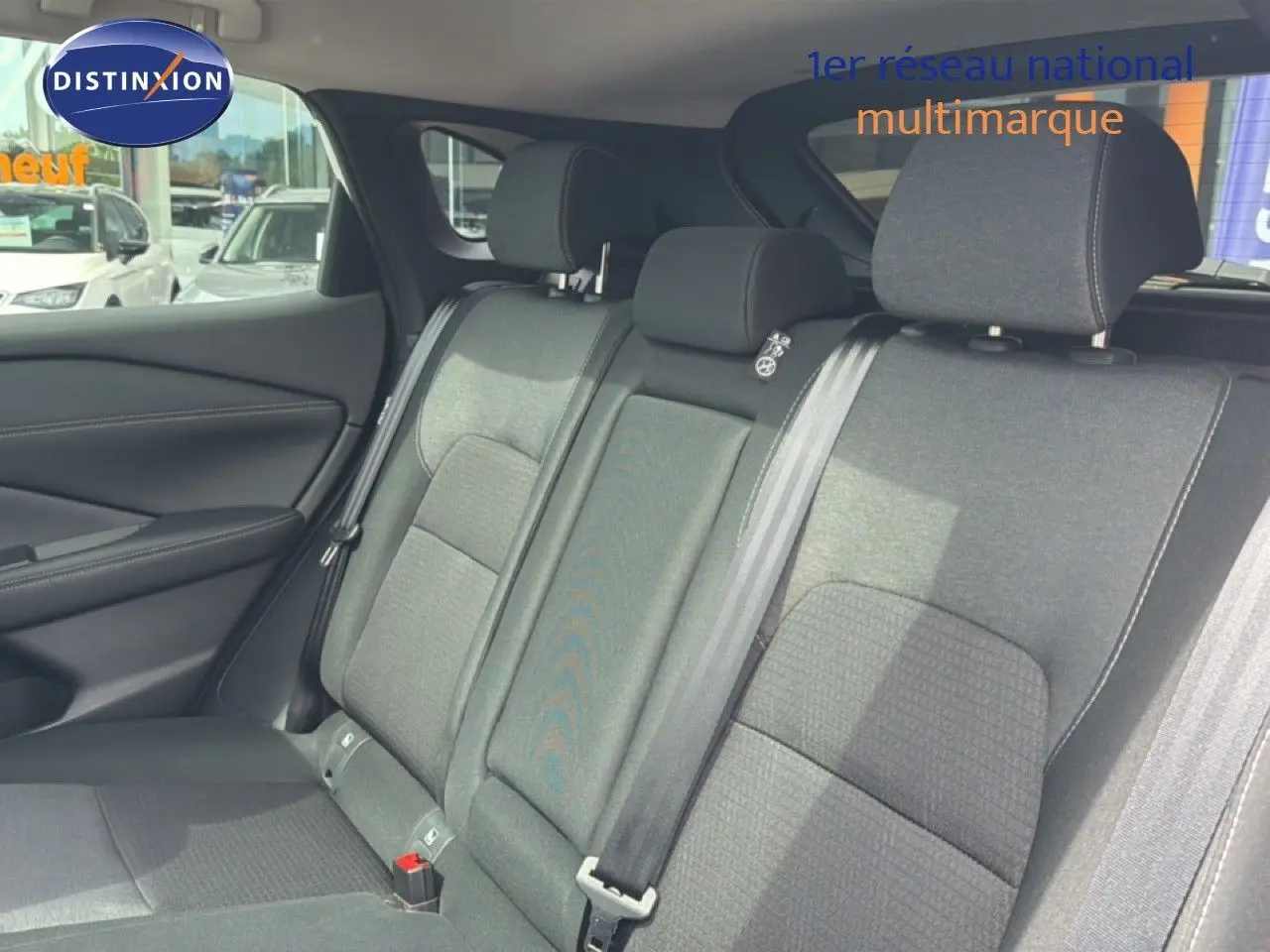 Vue intérieure des sièges arrière en tissu gris du Nissan Qashqai e-POWER 2023, avec ceintures de sécurité visibles.