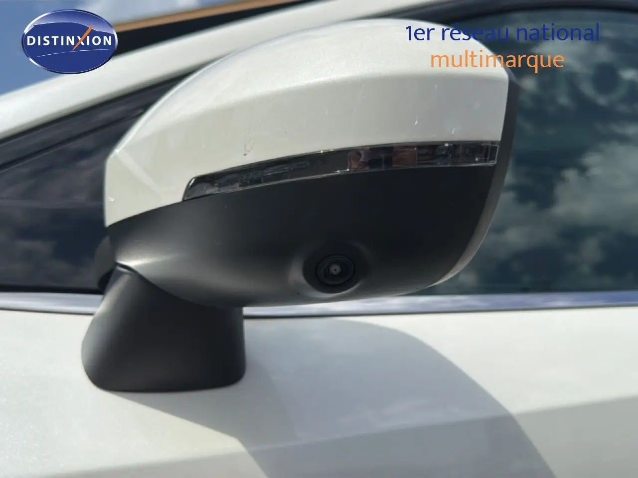 Gros plan sur le rétroviseur blanc nacré du Nissan Qashqai e-POWER 2023 avec caméra intégrée sous la coque noire.