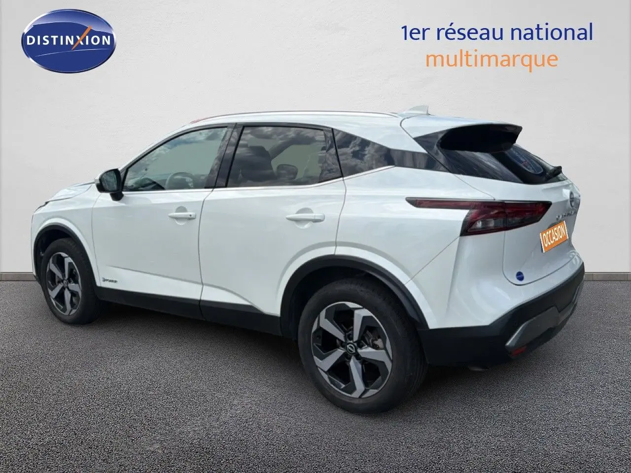 Vue 3/4 arrière côté droit d'un Nissan Qashqai blanc nacré métallisé avec jantes bi-ton et toit noir.