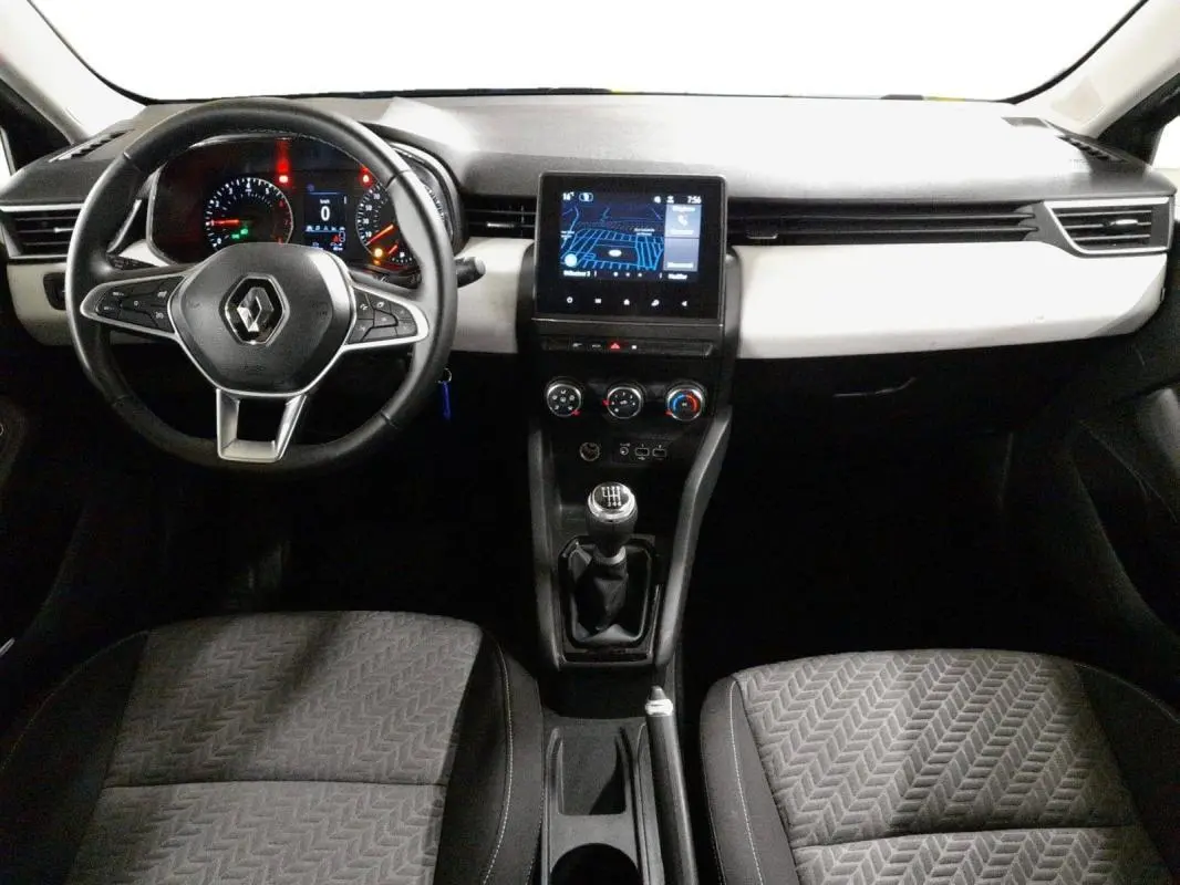 Vue intérieure avant centrée sur le tableau de bord et volant de la Renault Clio gris clair 2023 avec boîte manuelle.