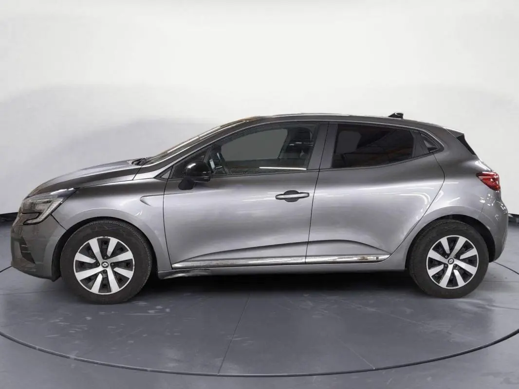 Vue de profil côté gauche d'une Renault Clio V TCe 90 Evolution gris clair de 2023 avec jantes alliage et vitres teintées.