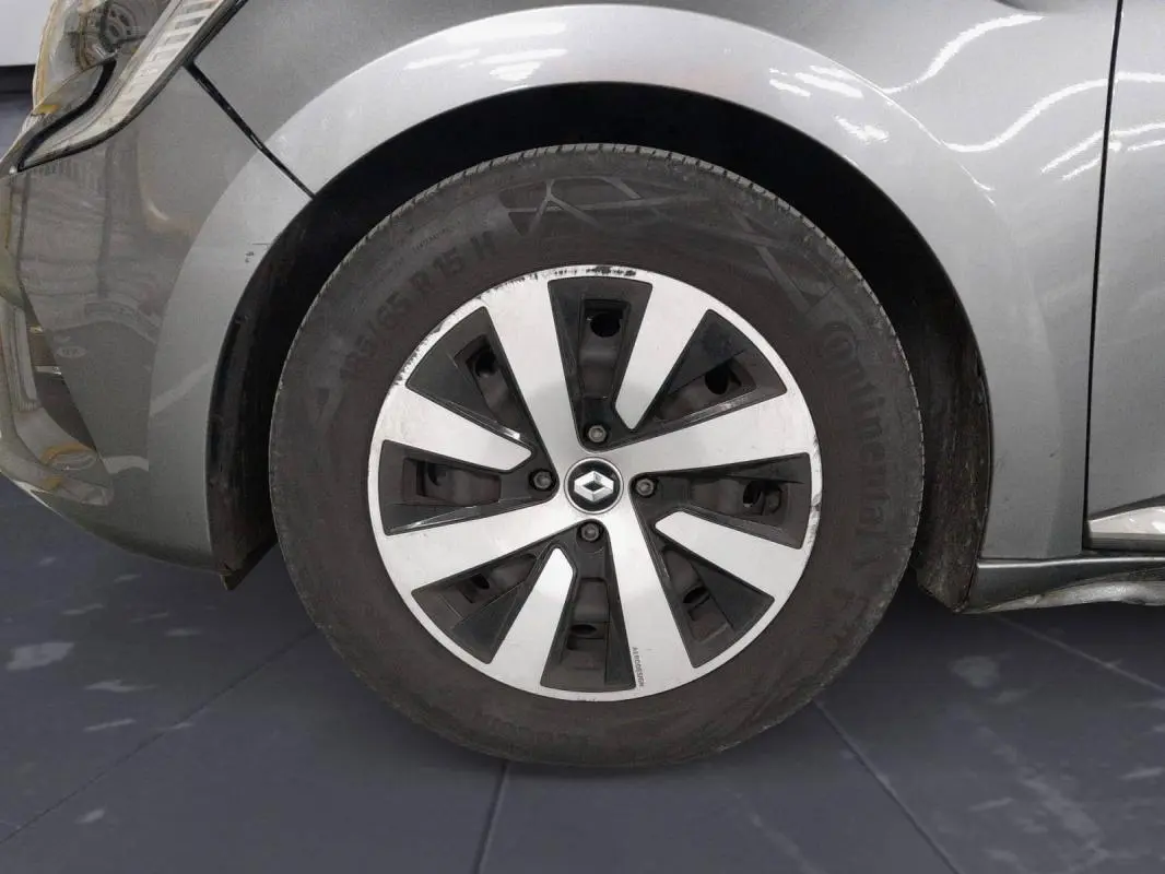 Gros plan sur la roue avant gauche gris clair d'une Renault Clio 2023 avec jante à motifs noirs et argentés.