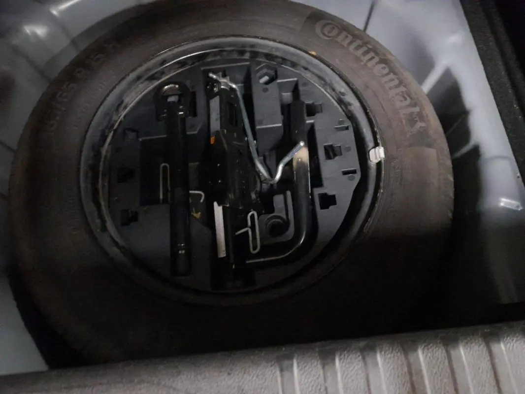 Gros plan sur la roue de secours et les outils de bord dans le coffre d'une Renault Clio gris clair 2023.