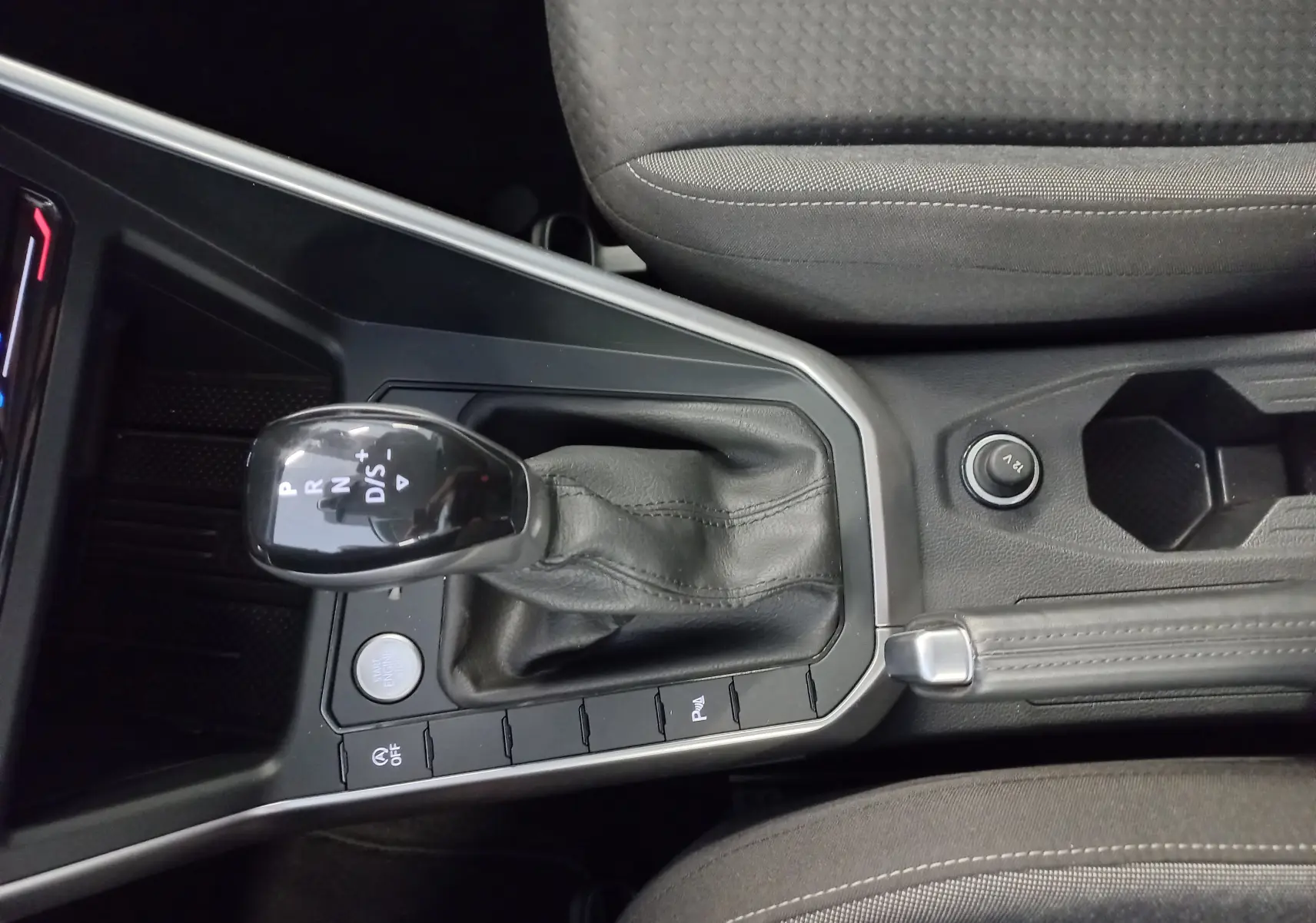 Vue rapprochée de la console centrale du Volkswagen Taigo 2025, avec levier de vitesse automatique et bouton start/stop.
