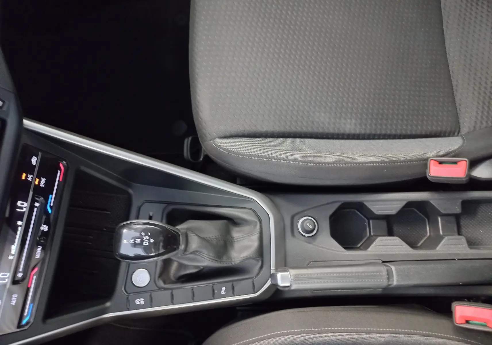 Vue intérieure centrée sur la console centrale du Volkswagen Taigo bleu récif, montrant levier de vitesse DSG et sièges gris.