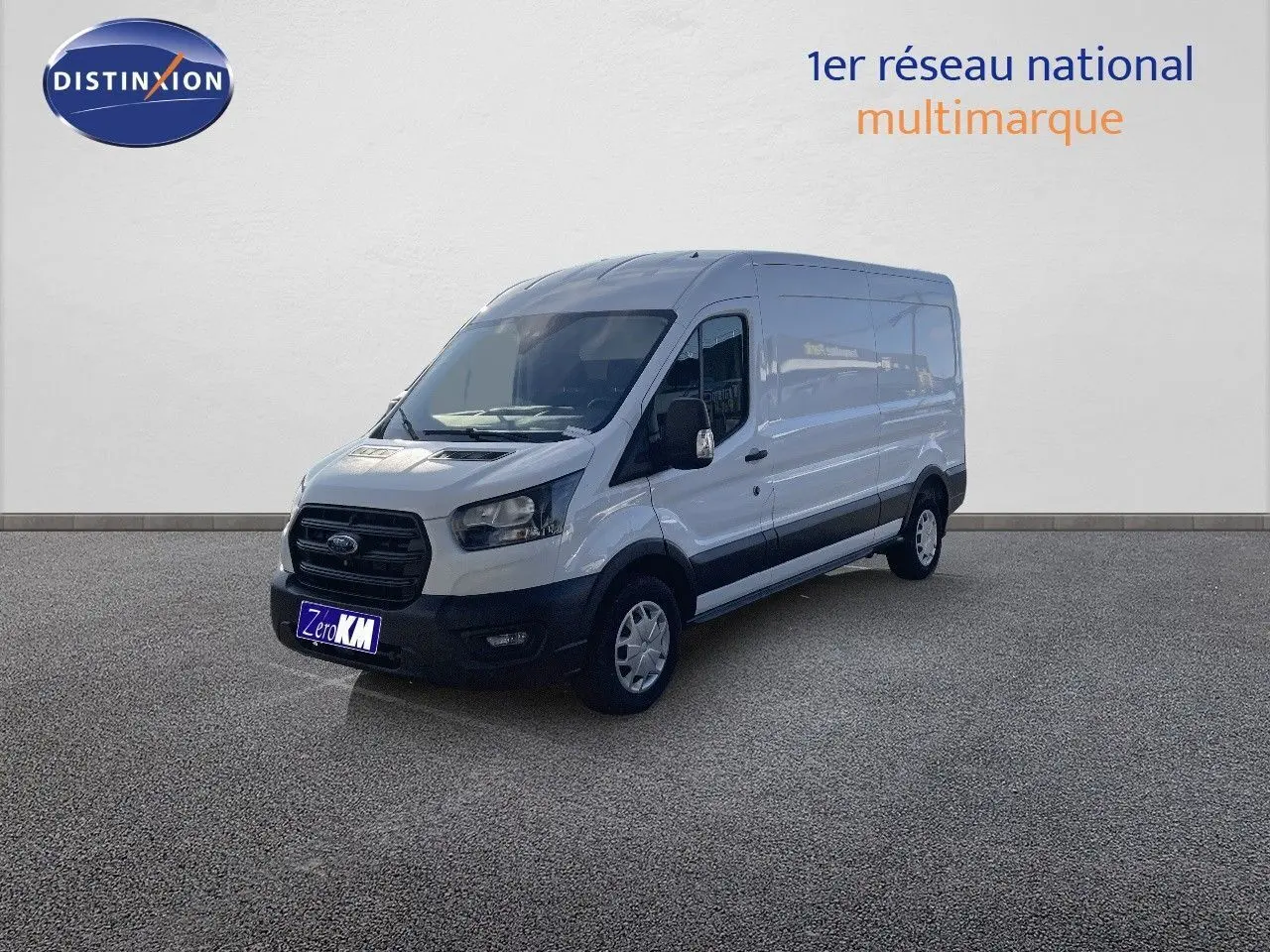 Fourgon Ford Transit blanc vu en 3/4 avant droit, avec carrosserie haute et longue, stationné devant un mur clair.