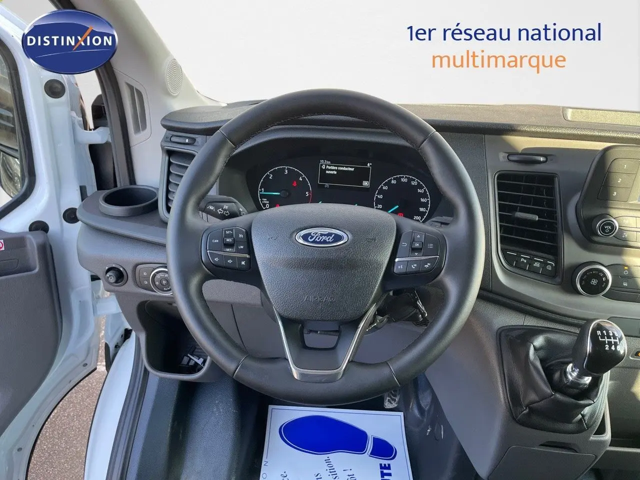 Vue intérieure centrée sur le volant et le levier de vitesses manuel du Ford Transit Fourgon blanc 2023.