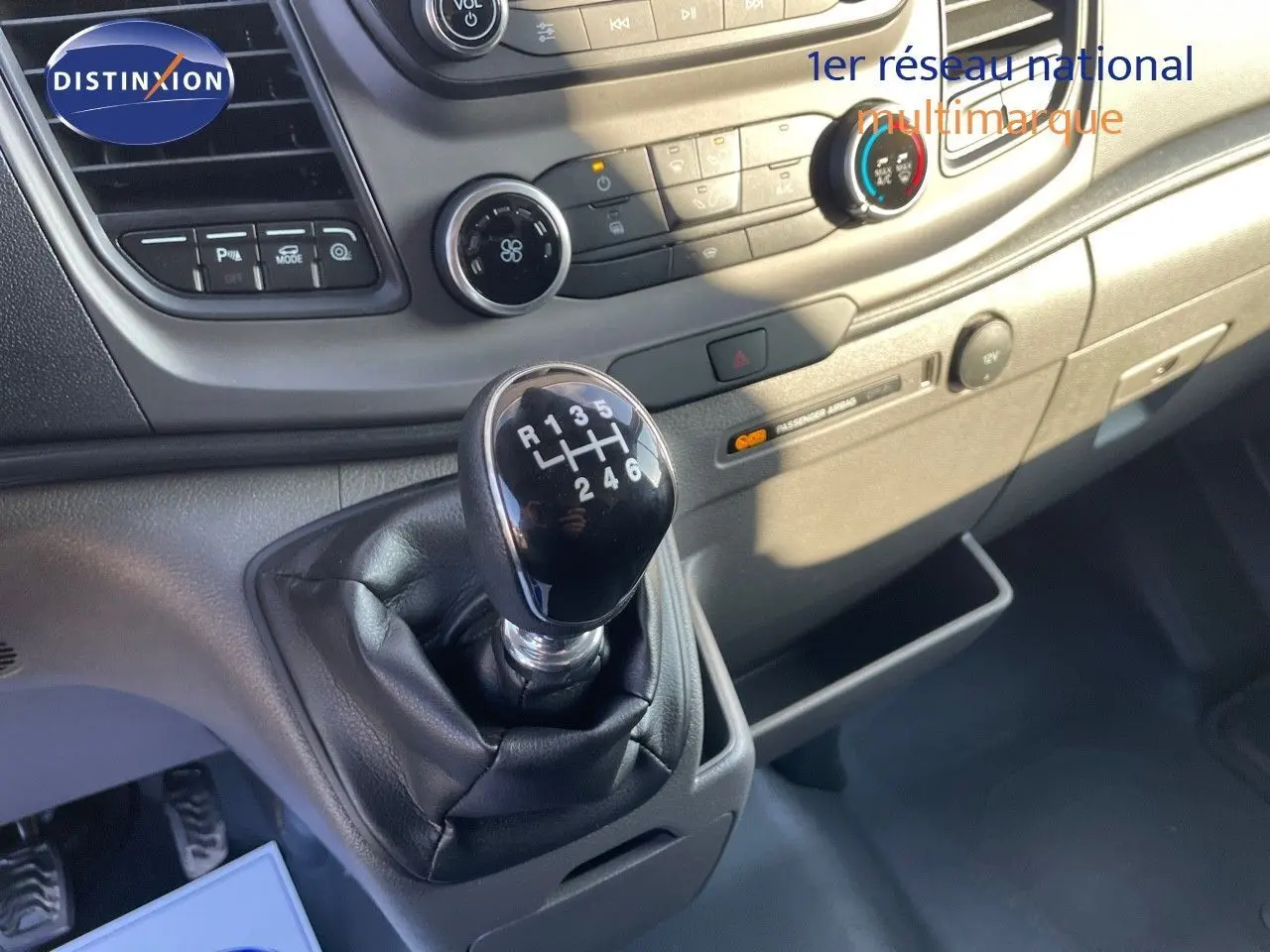 Gros plan sur le levier de vitesses manuel noir dans l'habitacle clair du Ford Transit Fourgon blanc 2023.