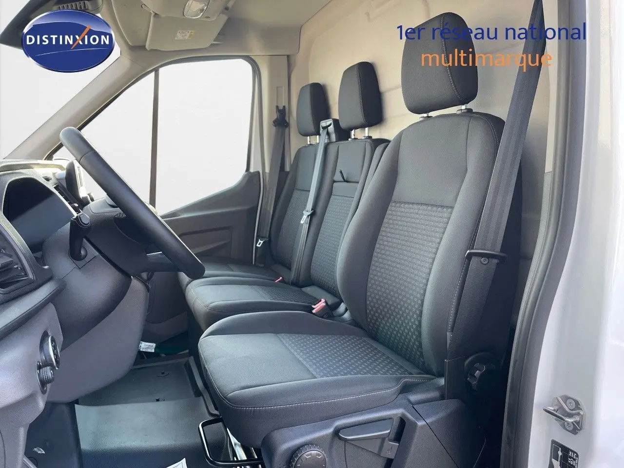 Vue intérieure côté conducteur du Ford Transit Fourgon blanc 2023, montrant les sièges noirs et le volant.