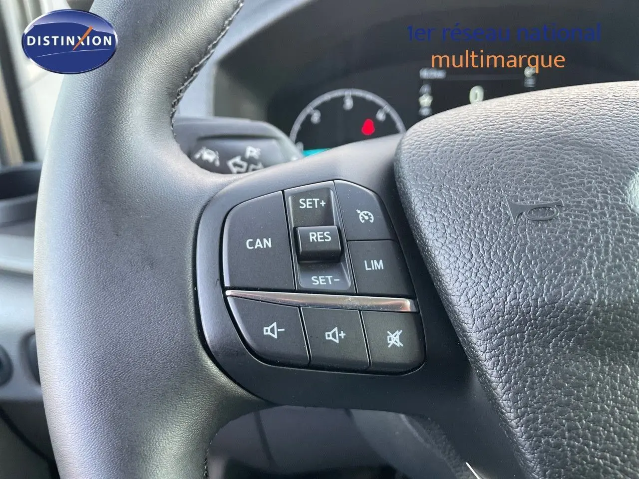 Gros plan sur les commandes de régulateur et volume au volant noir du Ford Transit Fourgon blanc 2023.
