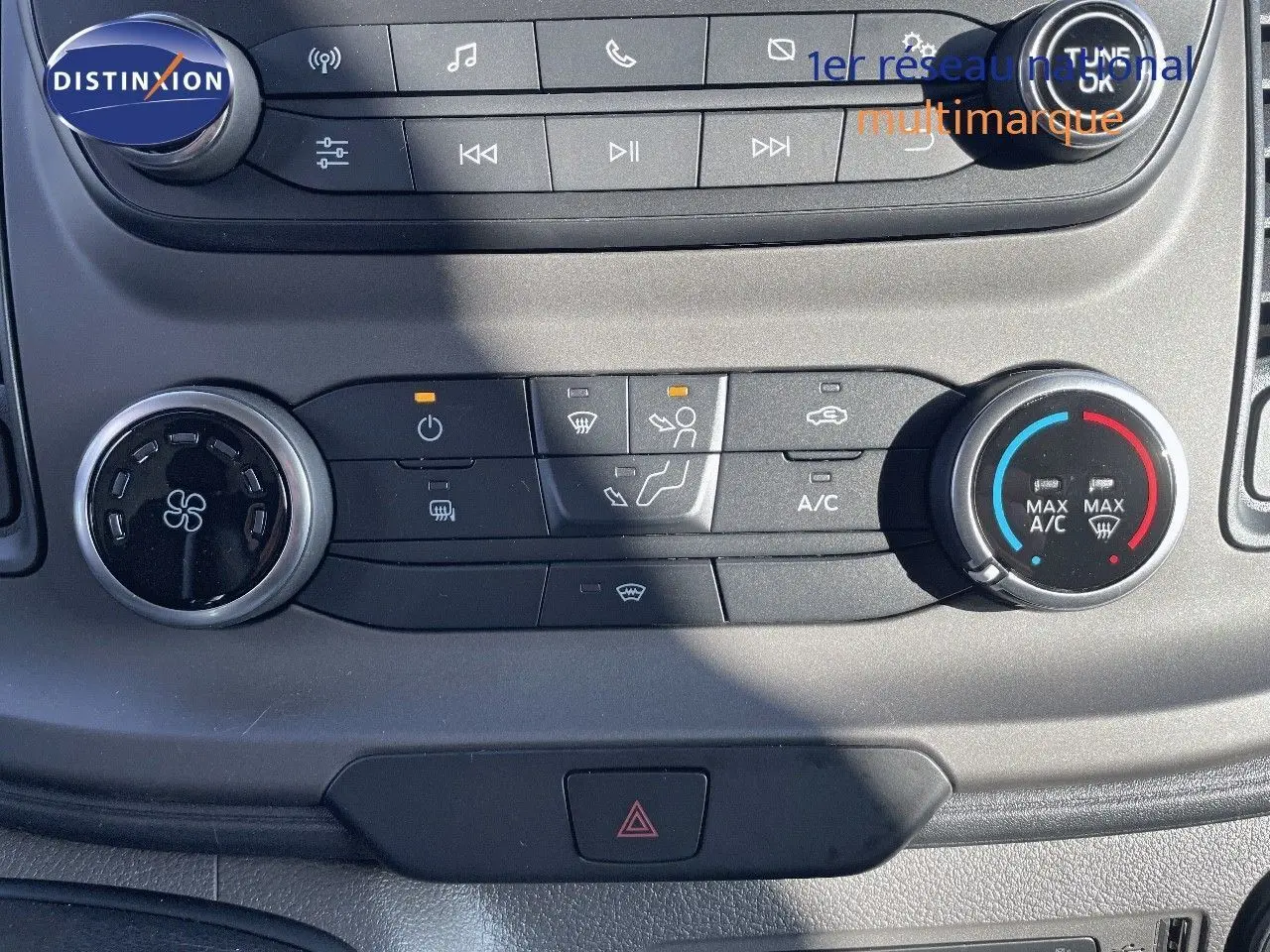 Vue rapprochée des commandes de climatisation du Ford Transit Fourgon blanc 2023 avec boutons rotatifs et réglages affichés.