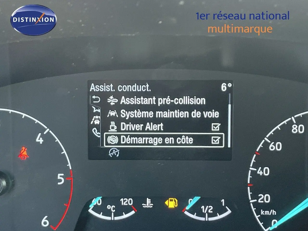 Vue rapprochée du tableau de bord du Ford Transit Fourgon blanc 2023 montrant les aides à la conduite activées.