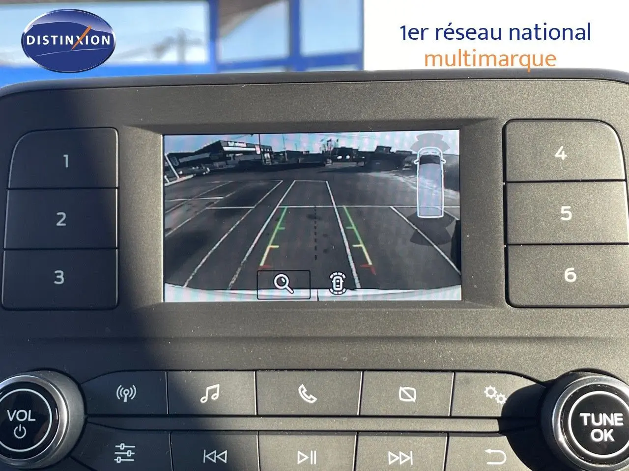 Écran de caméra de recul du Ford Transit Fourgon blanc 2023, affichant les lignes de guidage sur un parking vide.