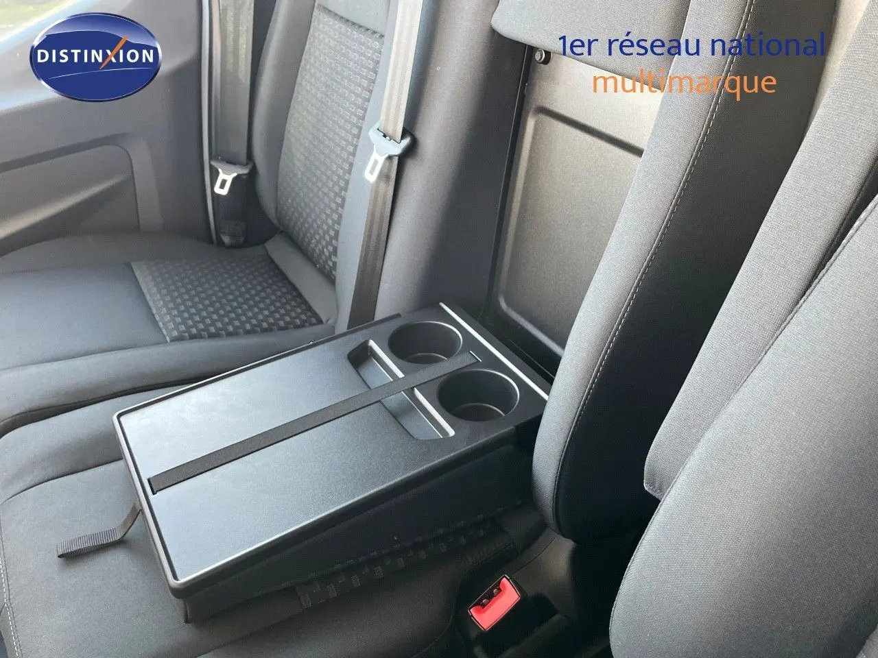 Intérieur du Ford Transit Fourgon 2023 montrant les sièges noirs et une tablette centrale avec porte-gobelets.