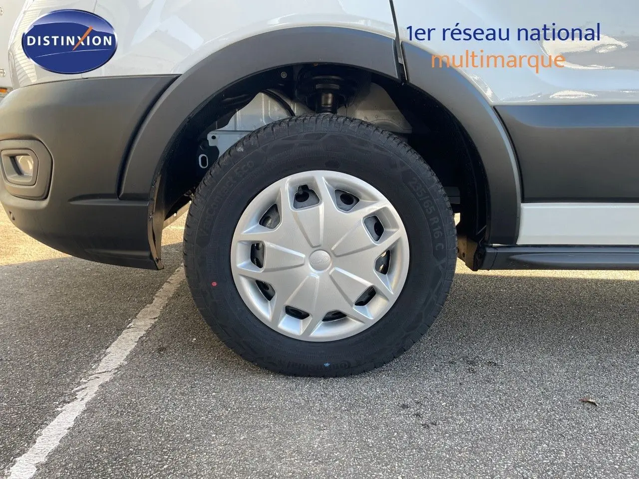 Gros plan sur la roue avant gauche d'un Ford Transit Fourgon blanc 2023 avec enjoliveur argenté et pare-chocs noir.