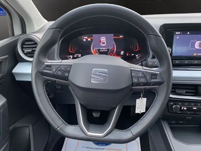 Vue centrée sur le volant du SEAT Ibiza 2023, avec tableau de bord numérique et commandes intégrées en noir.