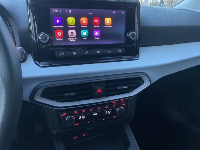 Tableau de bord de la SEAT Ibiza 2023 en blanc candy, vue centrée sur l'écran tactile et commandes de climatisation.