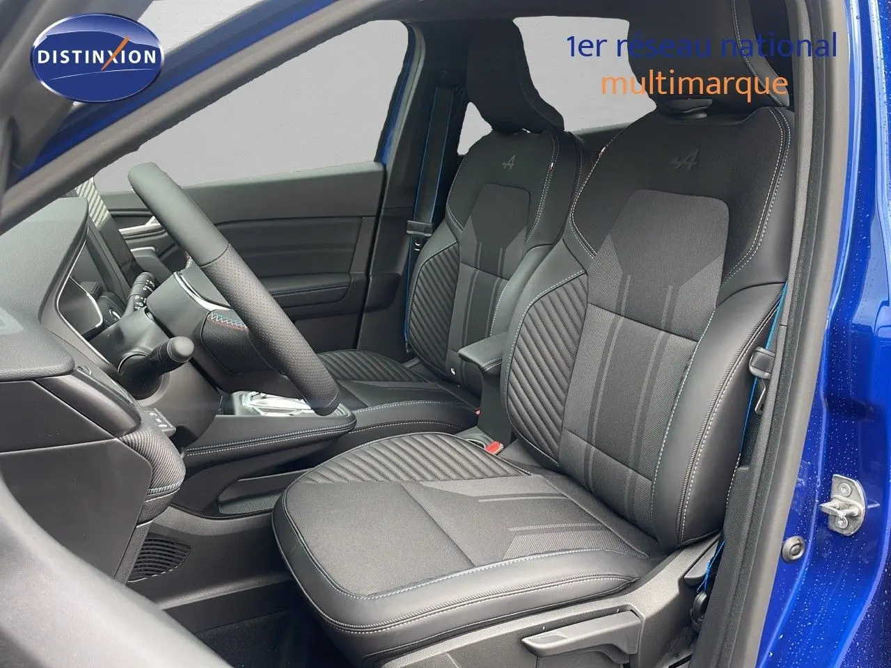 Intérieur avant du Renault Captur E-Tech hybride 2025, sièges noirs avec surpiqûres bleues et logo Alpine brodé.