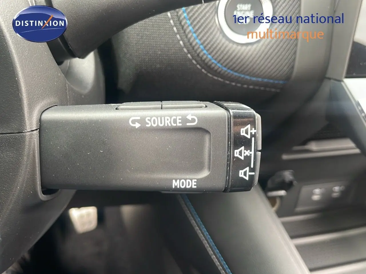 Gros plan sur la commande au volant du Renault Captur E-Tech hybride 2025 avec surpiqûres bleues et bouton Start visible.