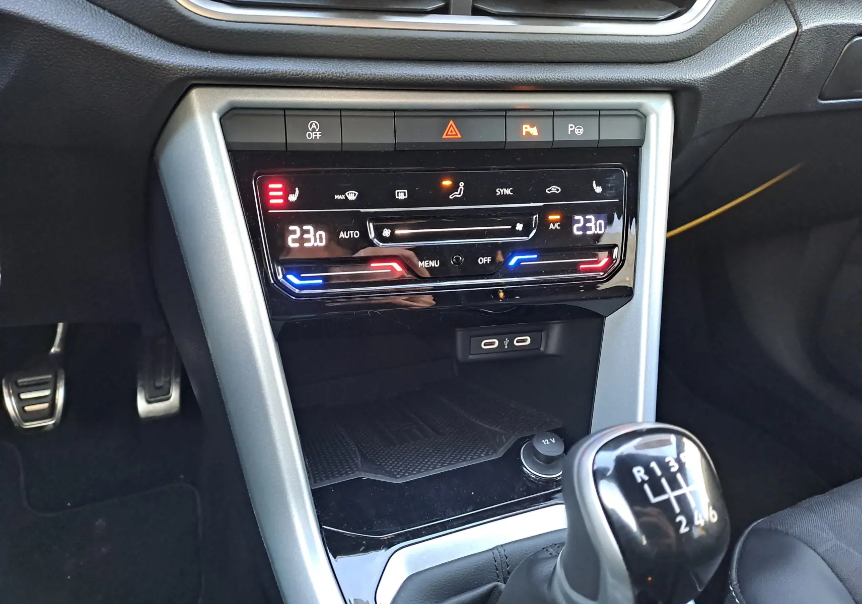 Gros plan sur la console centrale intérieure du Volkswagen T-Roc gris Ascot, avec climatisation digitale et levier de vitesse manuel.