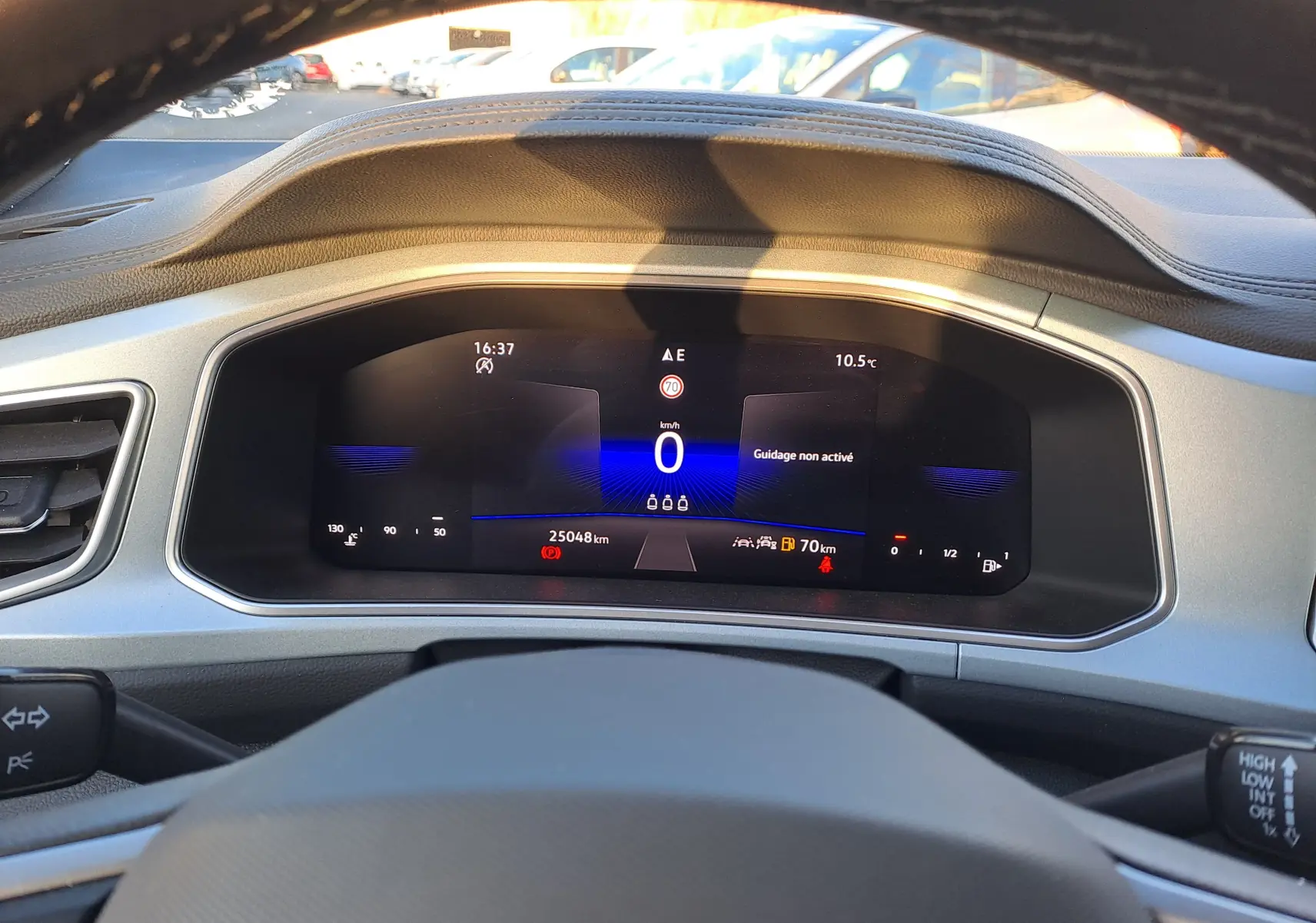 Vue intérieure du tableau de bord numérique du Volkswagen T-Roc gris Ascot, affichant 25 048 km et informations de conduite.