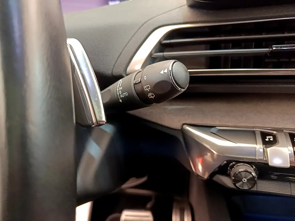 Gros plan sur la commande d’essuie-glace à gauche du volant dans l’habitacle noir du Peugeot 3008 GT rouge 2021.