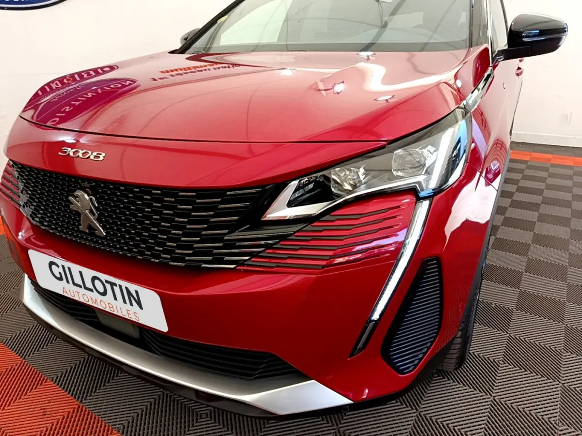 Vue 3/4 avant droit d'un Peugeot 3008 rouge avec calandre noire et feux LED distinctifs en griffes.
