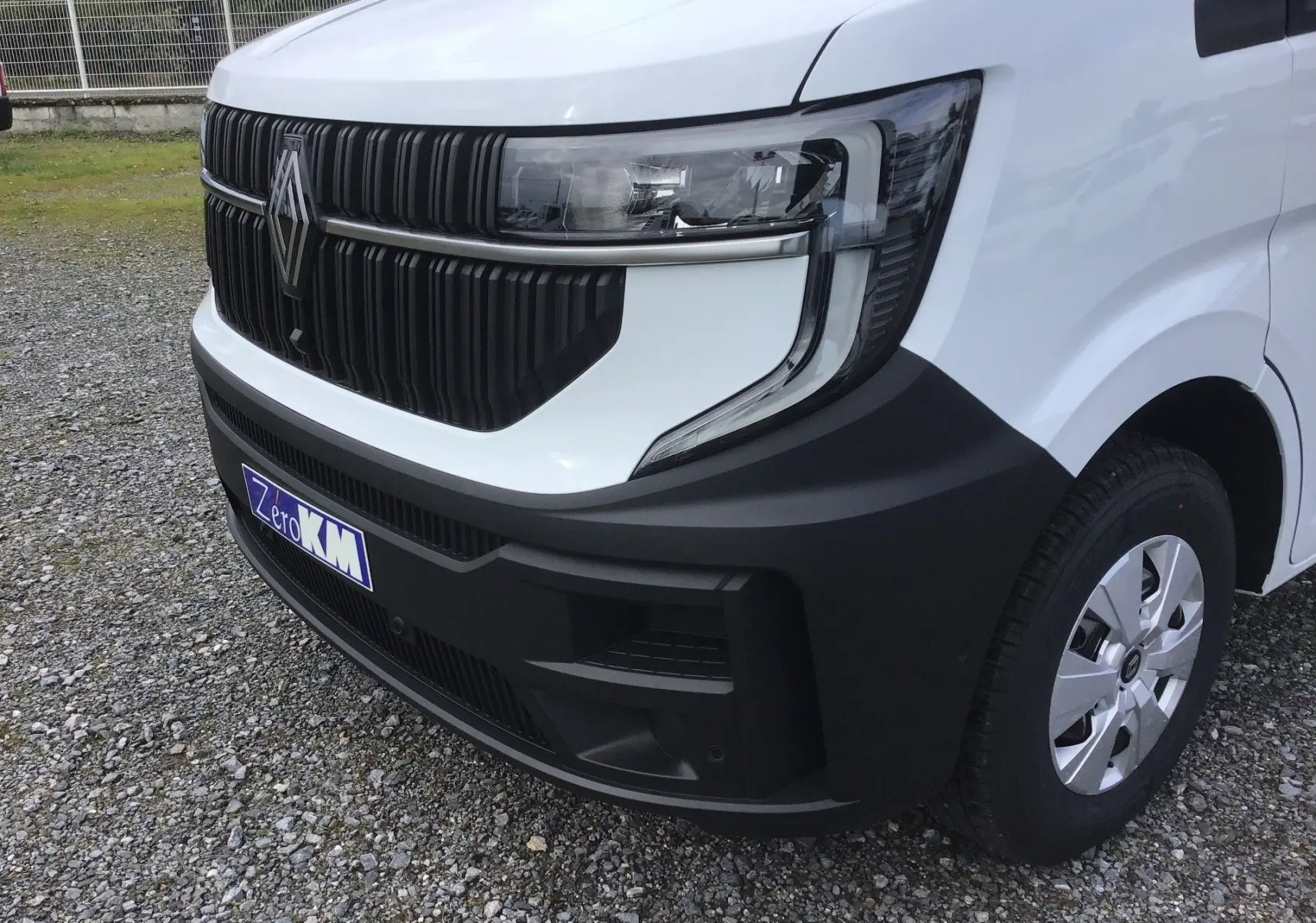 Gros plan 3/4 avant droit du Renault Master blanc, mettant en valeur la calandre noire et le phare moderne.