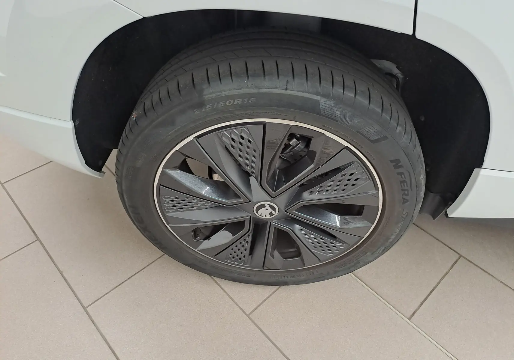 Gros plan sur la roue avant droite du Skoda Karoq blanc lune 2025, avec jante noire au design moderne Sportline.